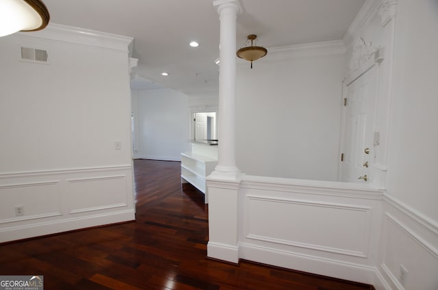 hallway with dark hardwood / wood-style floors, crown molding, and decorative columns