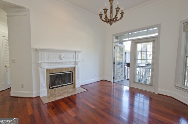 unfurnished living room with dark hardwood / wood-style flooring, ornamental molding, a fireplace, and an inviting chandelier