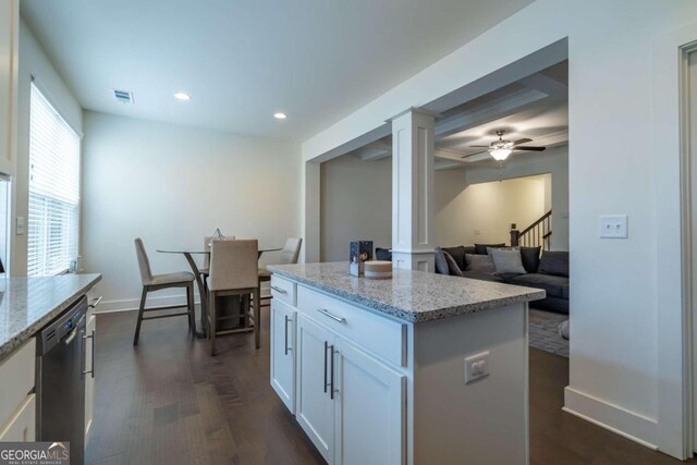 kitchen featuring dark wood-type flooring, white cabinets, stainless steel dishwasher, light stone countertops, and a kitchen island