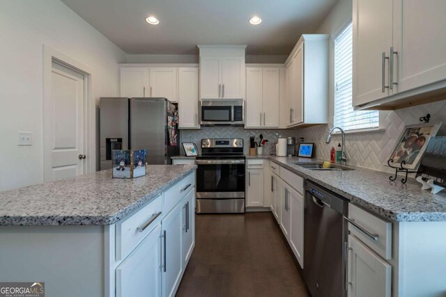 kitchen featuring backsplash, sink, dark hardwood / wood-style flooring, white cabinetry, and stainless steel appliances