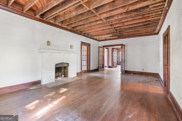 unfurnished living room with beamed ceiling, dark wood-type flooring, a tile fireplace, and french doors