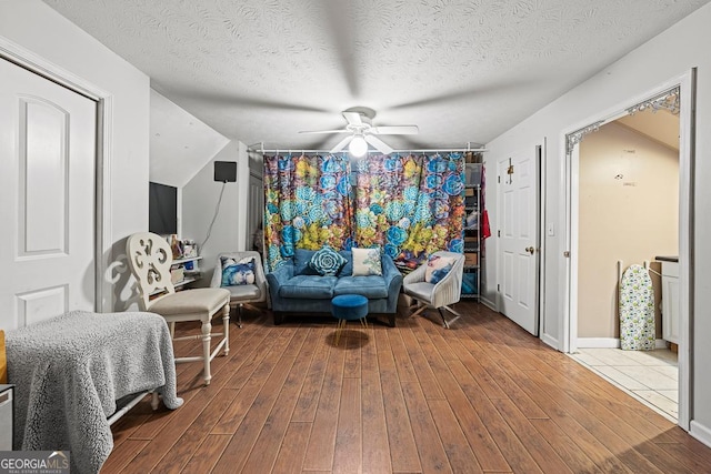 living area featuring hardwood / wood-style floors, a textured ceiling, and ceiling fan