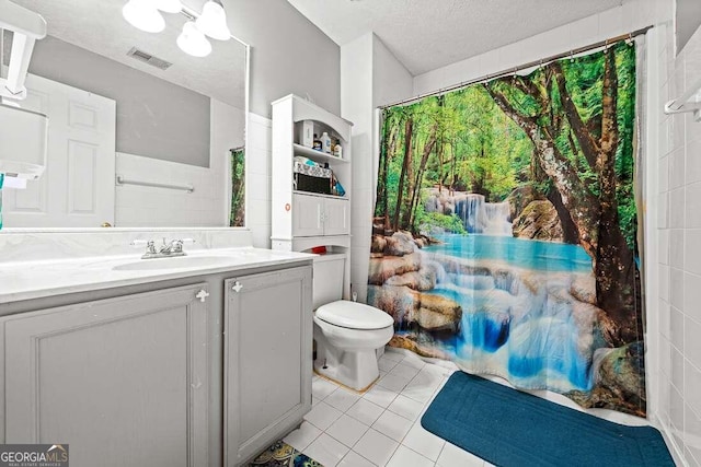 bathroom with tile patterned flooring, vanity, a textured ceiling, and toilet