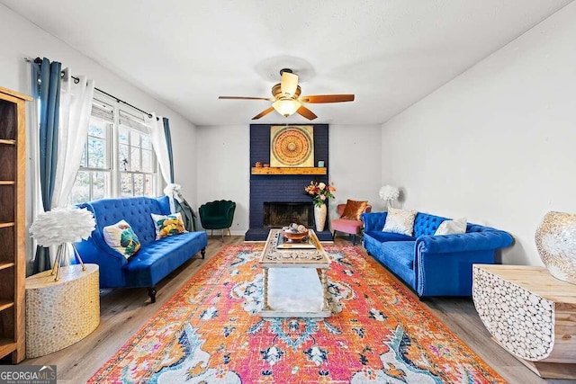 living room featuring wood-type flooring, a brick fireplace, and ceiling fan