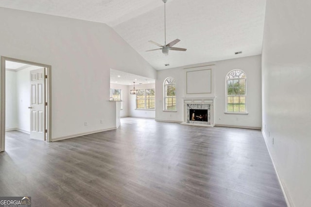 unfurnished living room with a textured ceiling, ceiling fan, high vaulted ceiling, a premium fireplace, and hardwood / wood-style floors