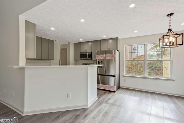 kitchen with gray cabinetry, stainless steel appliances, tasteful backsplash, light hardwood / wood-style flooring, and a textured ceiling