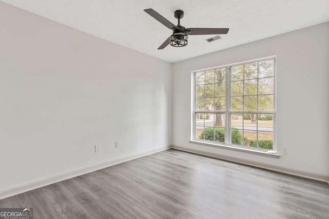 unfurnished room featuring ceiling fan, wood-type flooring, and a textured ceiling