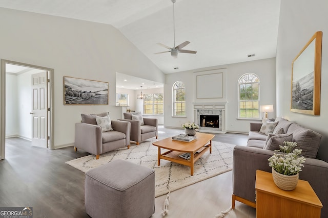 living room with ceiling fan, wood-type flooring, high vaulted ceiling, and a premium fireplace