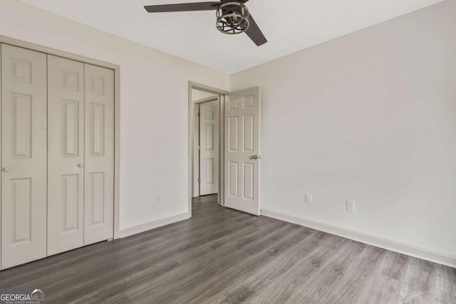 unfurnished bedroom featuring ceiling fan, dark hardwood / wood-style flooring, and a closet