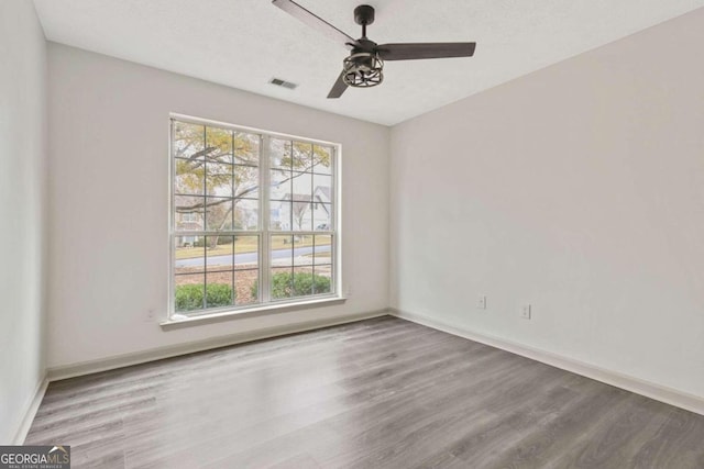 unfurnished room with ceiling fan, wood-type flooring, and a textured ceiling