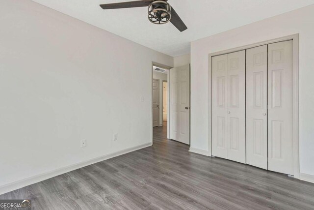 unfurnished bedroom with a closet, ceiling fan, and dark wood-type flooring