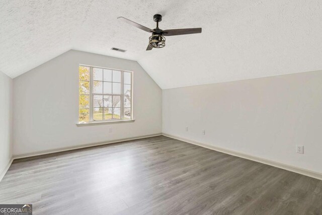 additional living space with hardwood / wood-style floors, ceiling fan, a textured ceiling, and vaulted ceiling