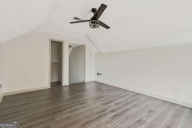 additional living space with ceiling fan, dark hardwood / wood-style flooring, a textured ceiling, and vaulted ceiling