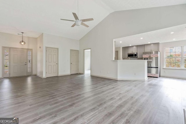 unfurnished living room featuring hardwood / wood-style flooring, high vaulted ceiling, and ceiling fan