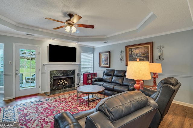 living room featuring dark hardwood / wood-style floors, a raised ceiling, and crown molding