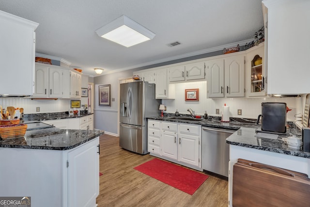 kitchen with white cabinets, sink, light wood-type flooring, ornamental molding, and stainless steel appliances