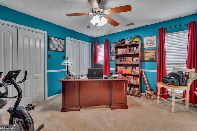 carpeted home office with ceiling fan and a textured ceiling