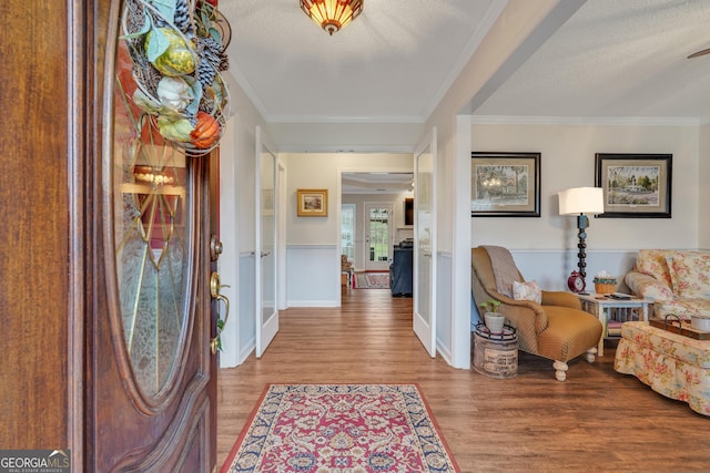 entryway featuring ornamental molding, a textured ceiling, and light hardwood / wood-style flooring