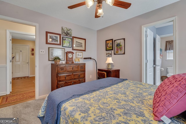 bedroom with ensuite bathroom, ceiling fan, and hardwood / wood-style flooring