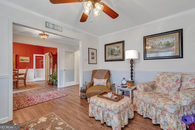 sitting room featuring wood-type flooring, a textured ceiling, ceiling fan, and crown molding