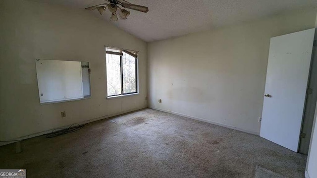 empty room with a textured ceiling, light colored carpet, vaulted ceiling, and ceiling fan