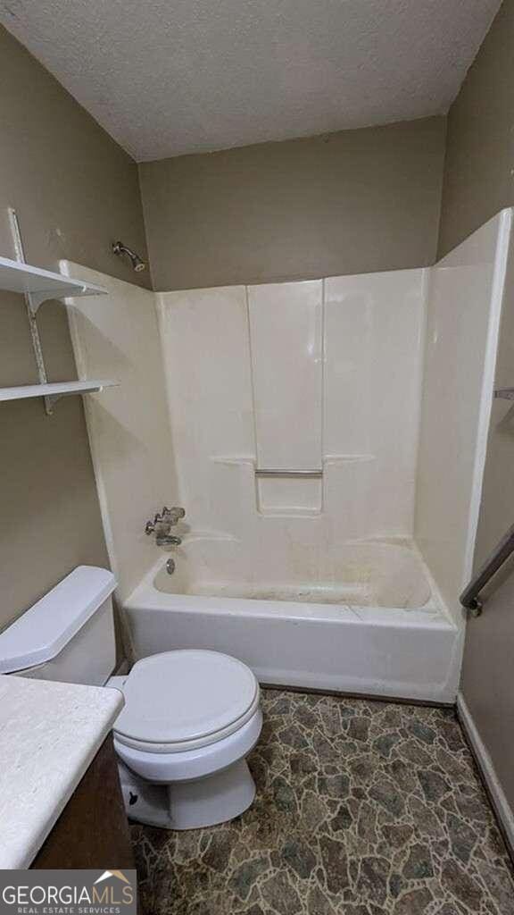 full bathroom featuring shower / washtub combination, vanity, a textured ceiling, and toilet