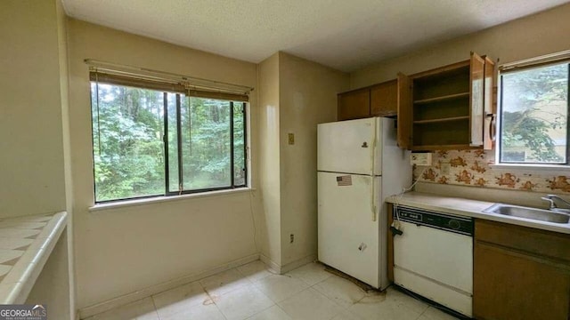 kitchen with a textured ceiling, white appliances, and sink