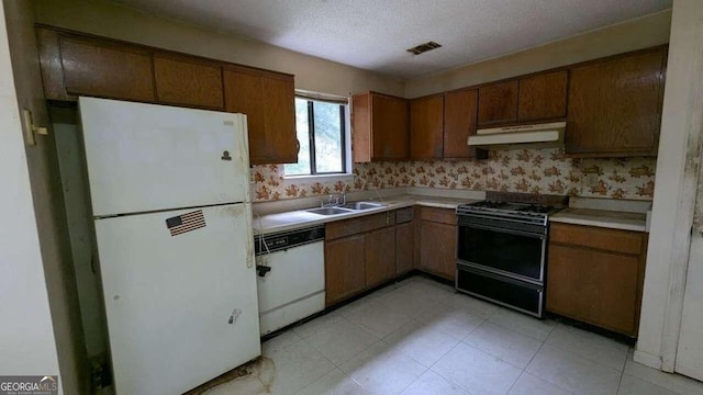 kitchen with a textured ceiling, white appliances, and sink