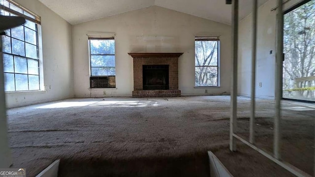 unfurnished living room with a fireplace, a healthy amount of sunlight, and lofted ceiling