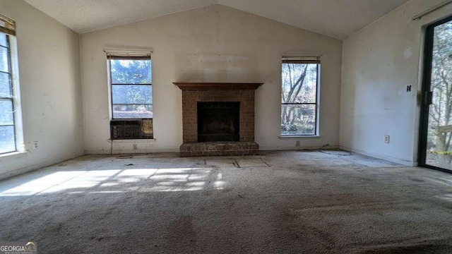 unfurnished living room featuring light carpet, a healthy amount of sunlight, lofted ceiling, and a brick fireplace