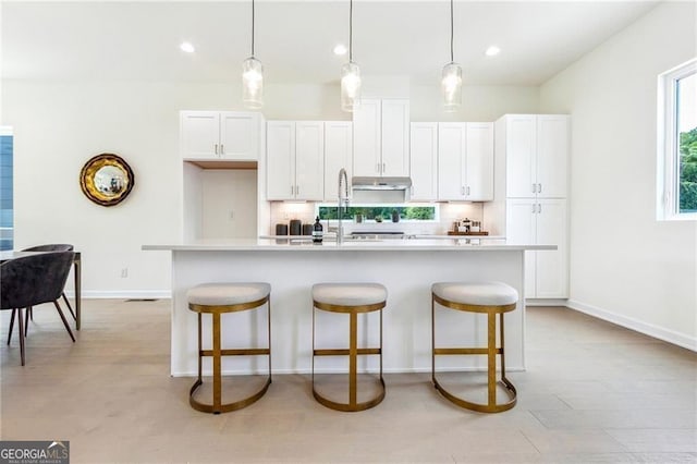 kitchen featuring white cabinets, pendant lighting, tasteful backsplash, and an island with sink