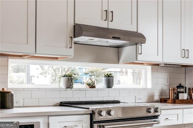 kitchen featuring stainless steel range oven, white cabinetry, and tasteful backsplash