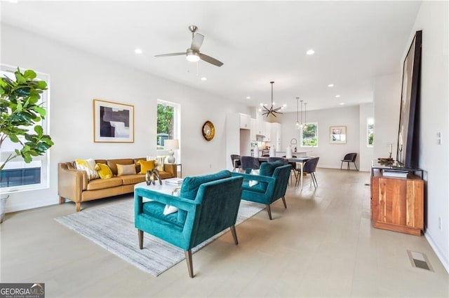 living room featuring ceiling fan with notable chandelier