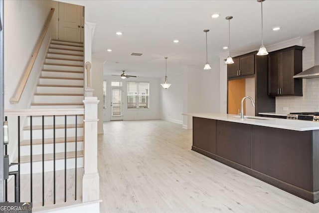 kitchen featuring dark brown cabinetry, ceiling fan, sink, light hardwood / wood-style flooring, and decorative backsplash