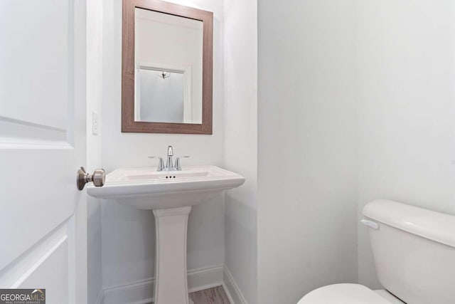 bathroom featuring wood-type flooring and toilet