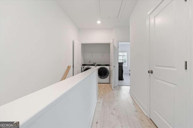 hall with washing machine and dryer and light hardwood / wood-style floors