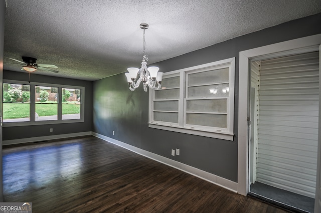 unfurnished dining area with a textured ceiling, ceiling fan with notable chandelier, and dark hardwood / wood-style floors