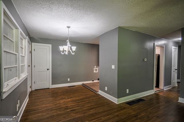 unfurnished room featuring dark hardwood / wood-style flooring, a textured ceiling, and a chandelier