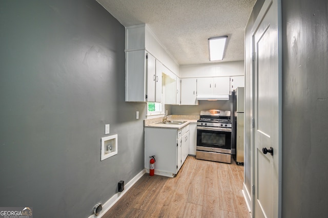 kitchen featuring white cabinets, sink, light wood-type flooring, a textured ceiling, and stainless steel appliances