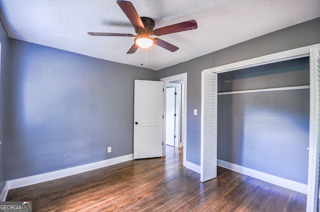 unfurnished bedroom with ceiling fan, dark hardwood / wood-style flooring, a textured ceiling, and a closet