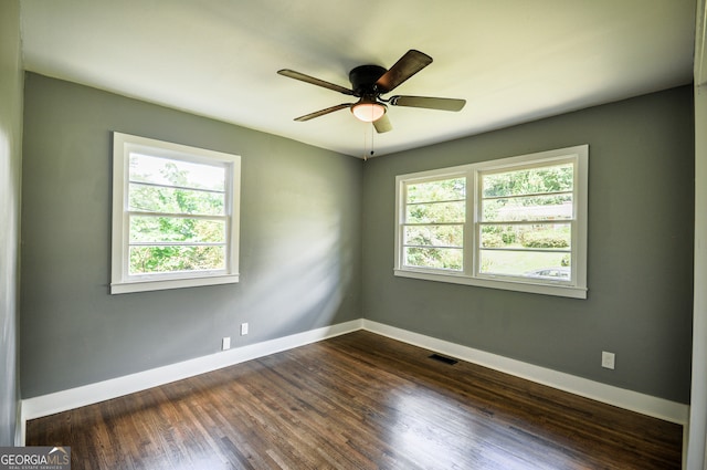 spare room with ceiling fan, a healthy amount of sunlight, and dark wood-type flooring