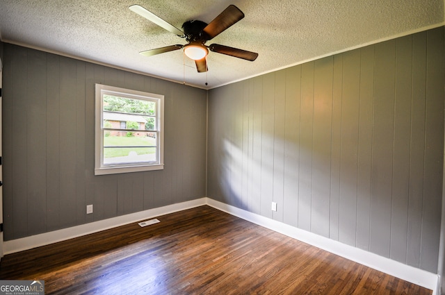 unfurnished room featuring wood walls, dark wood-type flooring, and a textured ceiling