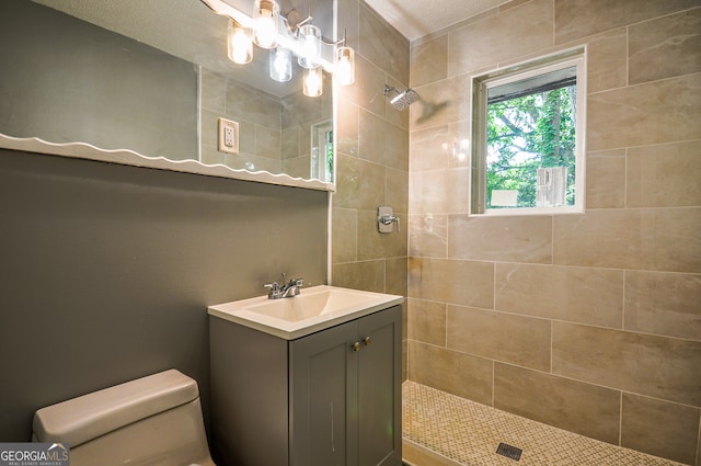 bathroom with a tile shower, vanity, a textured ceiling, and toilet