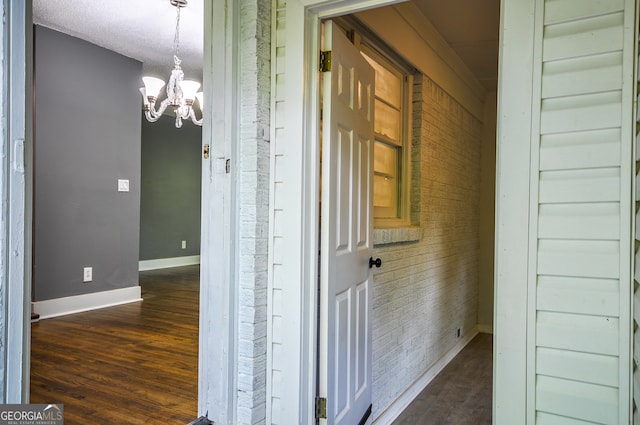 hallway with dark hardwood / wood-style flooring, a textured ceiling, and a notable chandelier