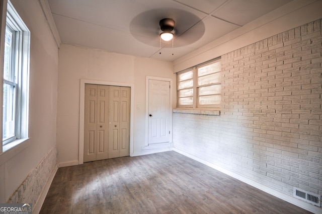 unfurnished bedroom featuring multiple windows, ceiling fan, a closet, and wood-type flooring