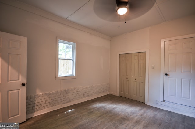 unfurnished bedroom with ceiling fan and dark wood-type flooring