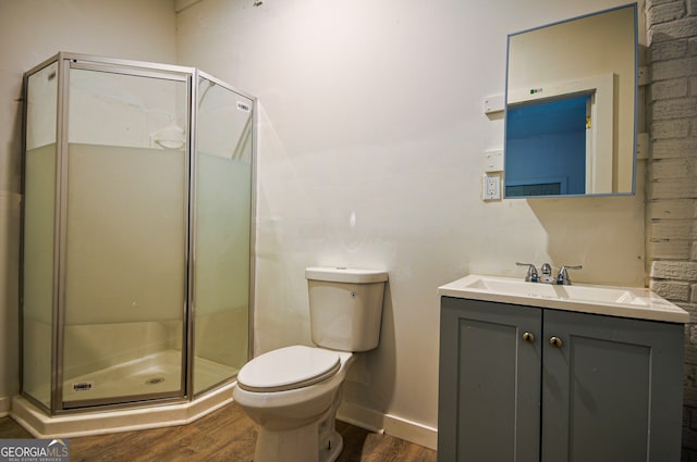 bathroom with hardwood / wood-style floors, vanity, a shower with door, and toilet