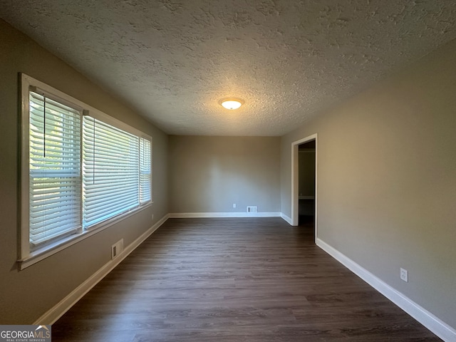 empty room featuring dark hardwood / wood-style floors and a textured ceiling