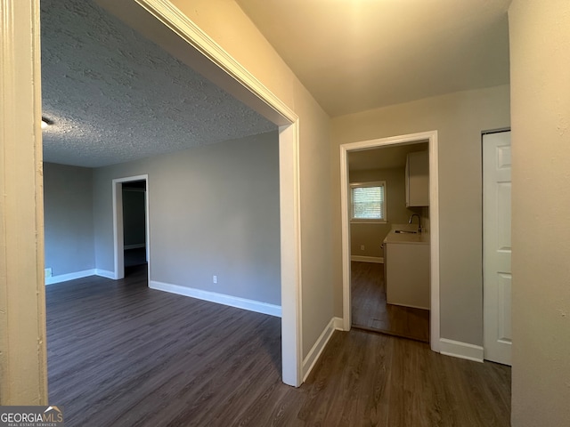 spare room with a textured ceiling, sink, and dark wood-type flooring