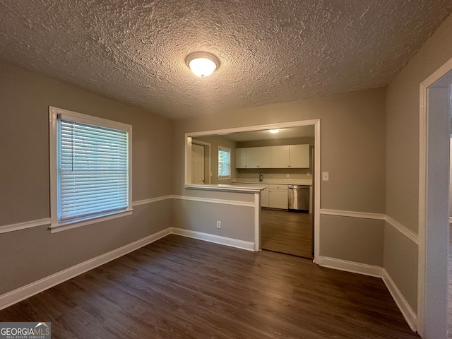 unfurnished dining area with dark wood-type flooring and a textured ceiling